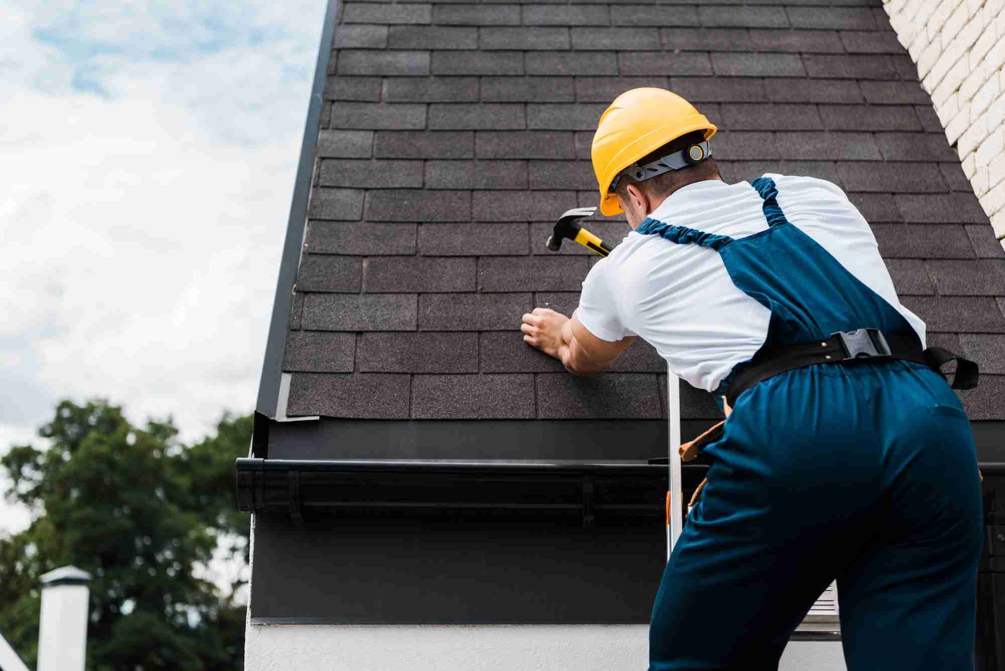 Roofer on a ladder repairing a roof edge