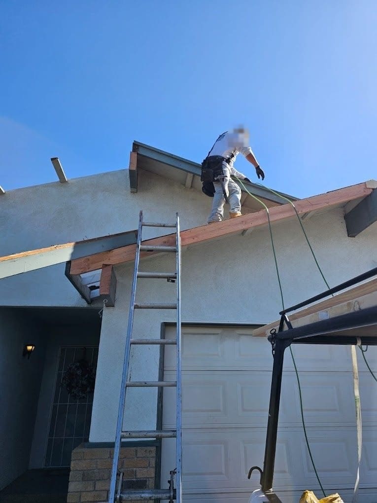 Roofer replacing rotted eave framing on a single-story home