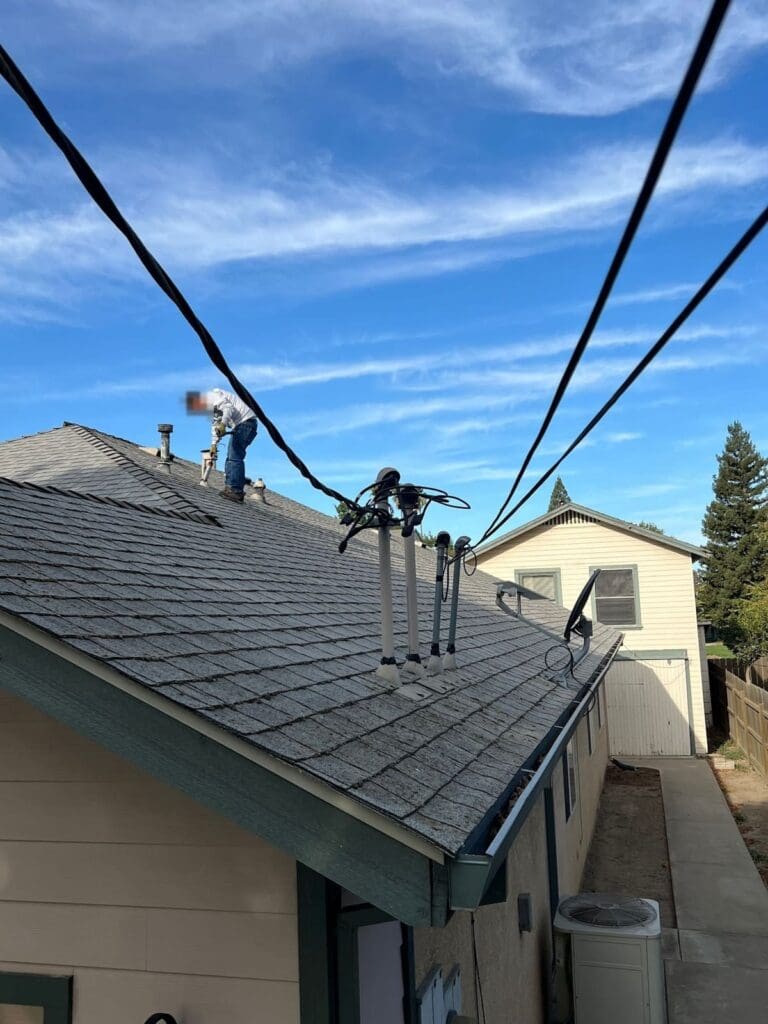 Roofer re-sealing pipe penetrations on a shingle roof